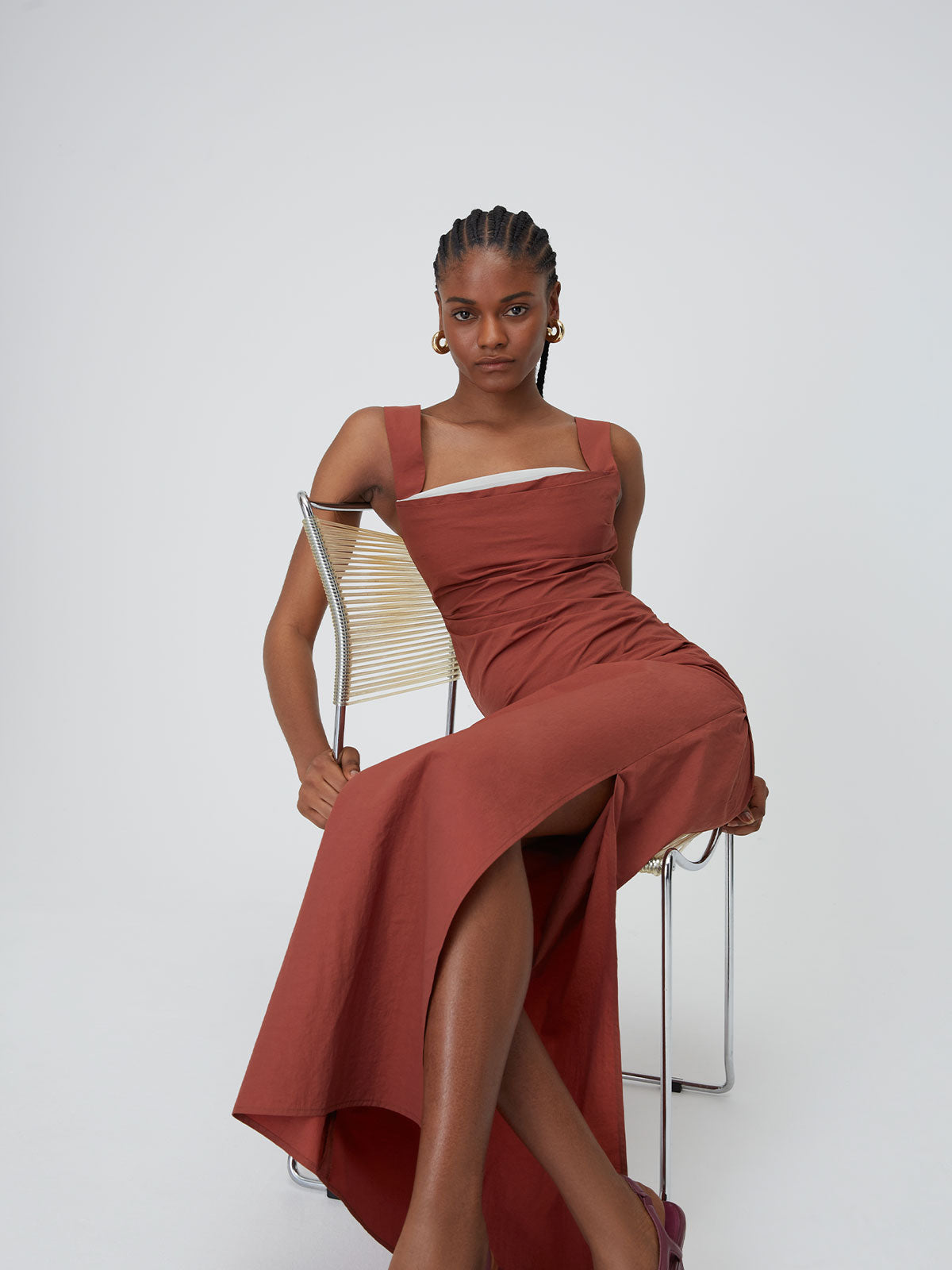 A female figure leaning against the backrest of a chair wearing the Spice 09 Raf Dress