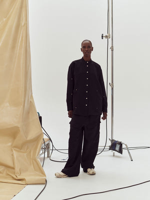 Front view of a model at a photoshoot wearing Black Herb Trouser
