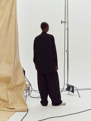Rear view of a model in a studio earing Black Herb Trousers