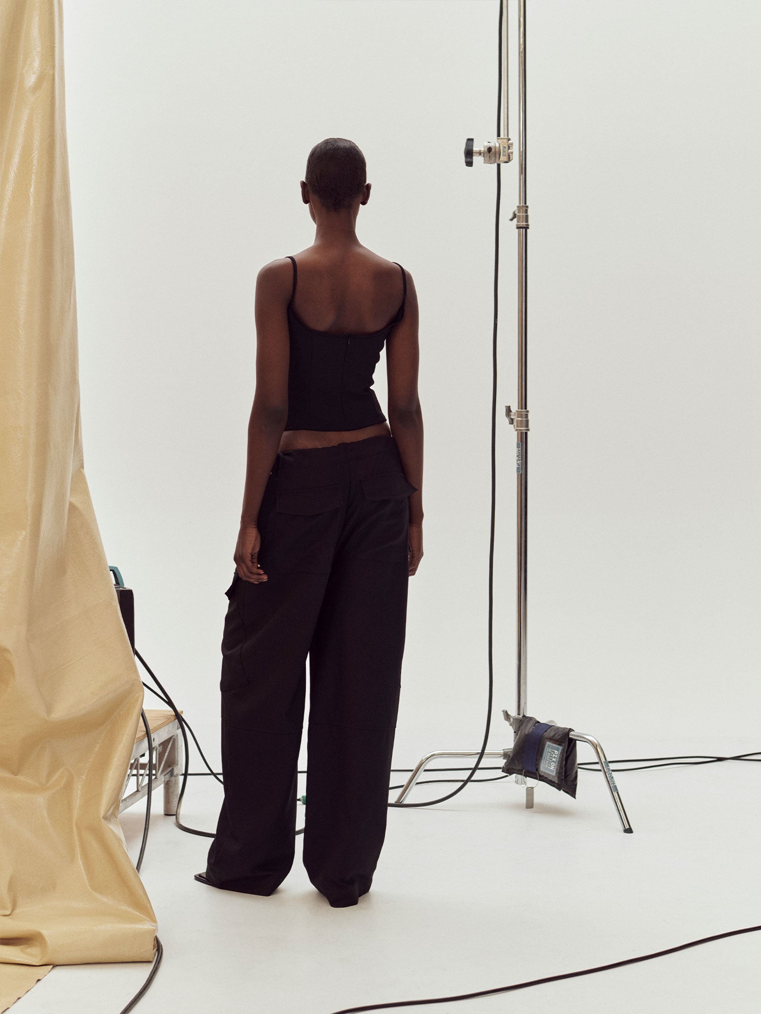 Rear view of a model standing near studio equipment wearing Black Marlo Singlet