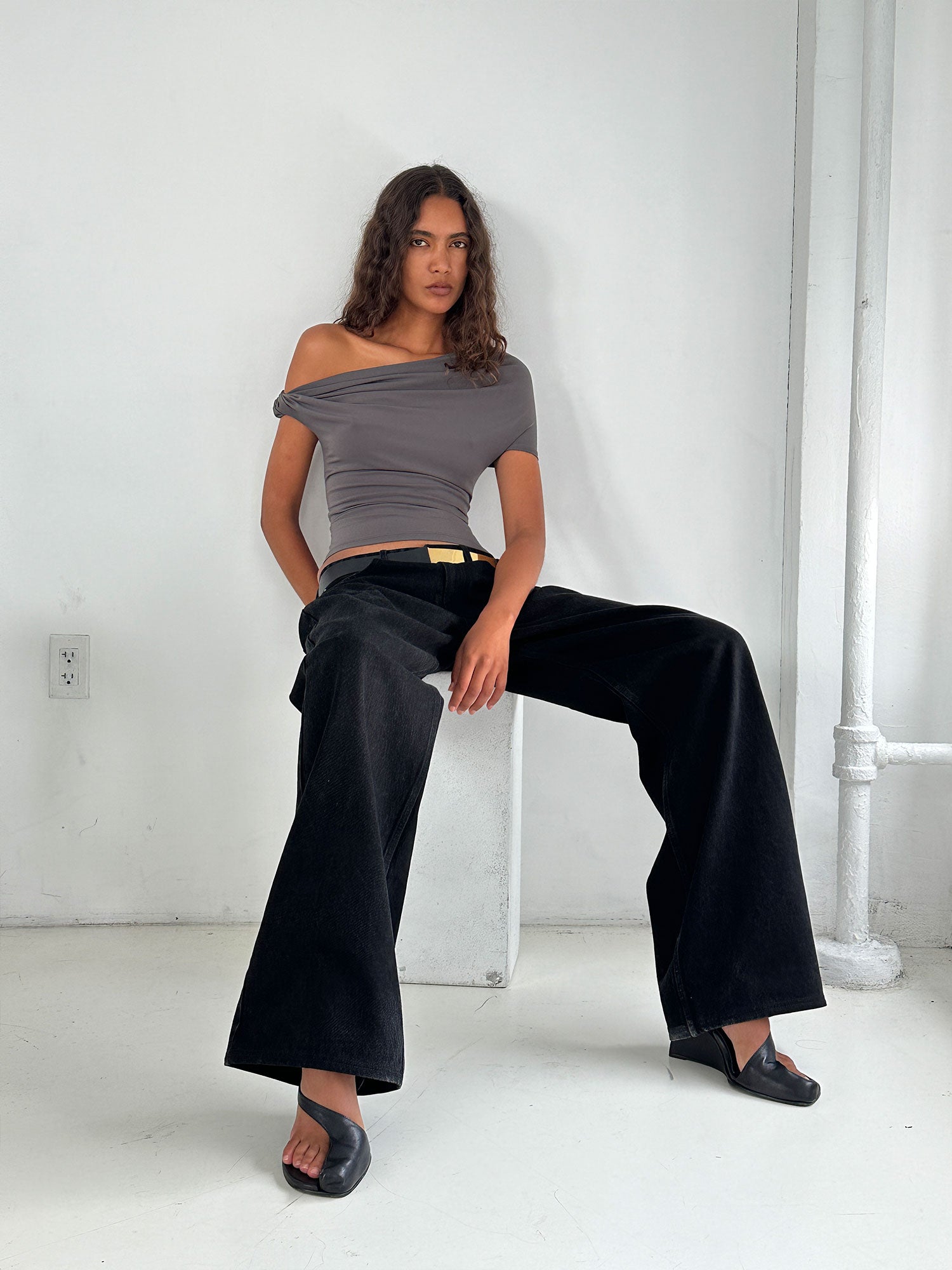 Model sitting down and leaning back against on a concrete slab wearing a Mushroom Elemental Ida Top 