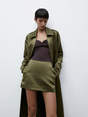 A model standing against a white background looking down at her feet wearing a matching Olive 09 Cass Mini Skirt and Duster Coat