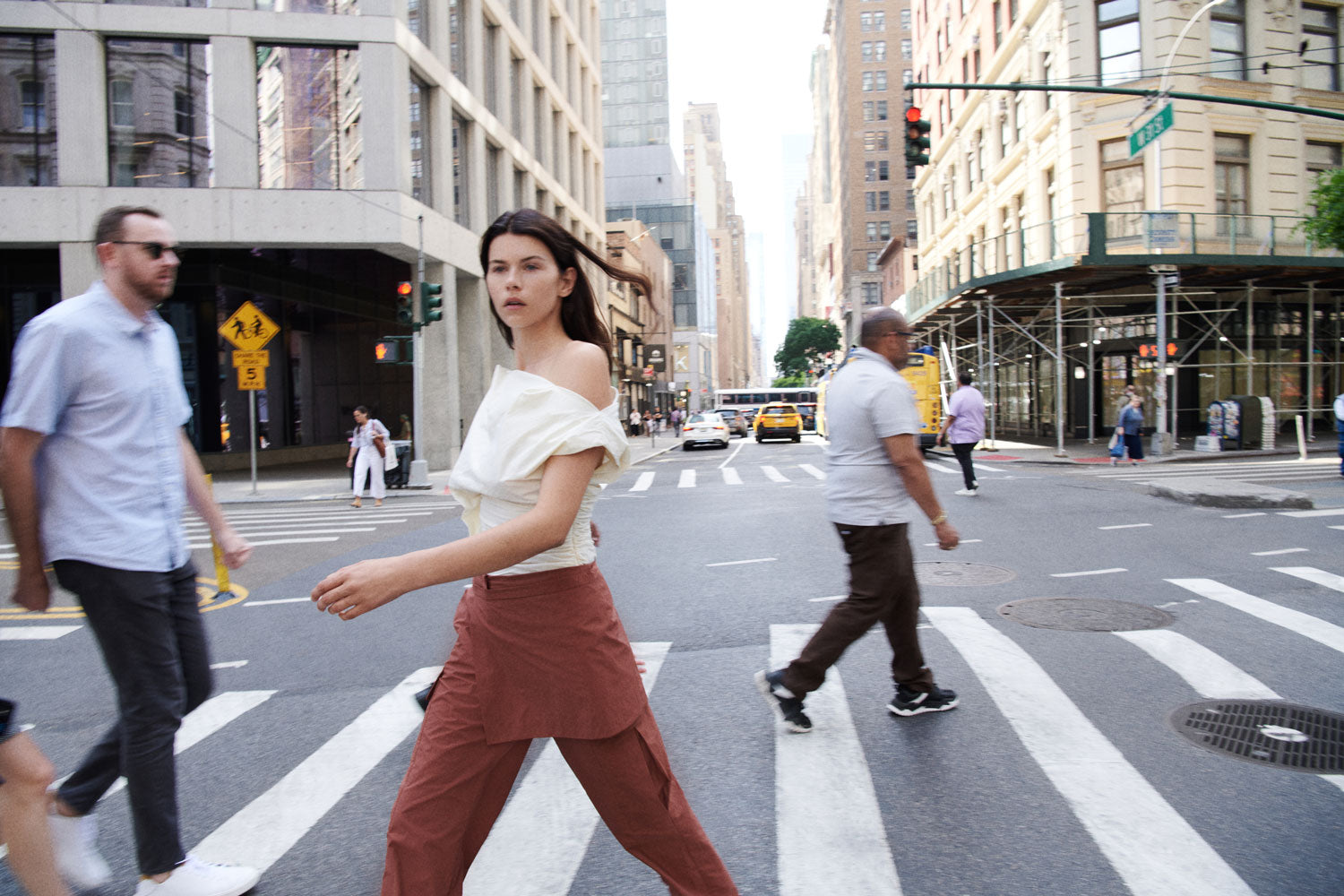 A female figure crossing a busy intersection wearing the Cream 09 Liquid Top