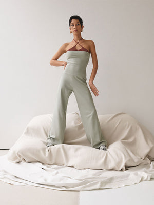 A woman standing wearing a sage-coloured jumpsuit.