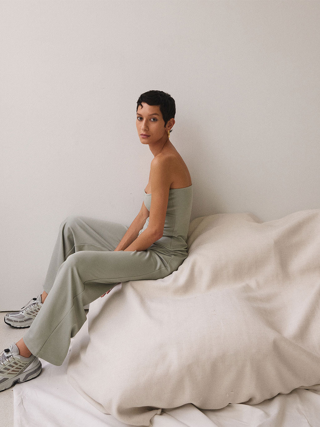 A woman sitting wearing a sage-coloured jumpsuit.