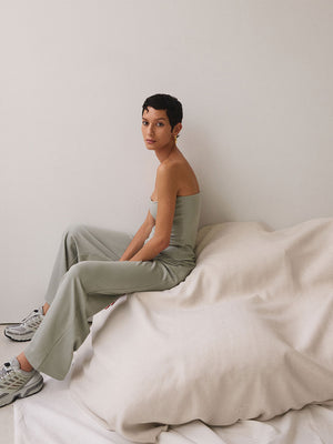 A woman sitting wearing a sage-coloured jumpsuit.