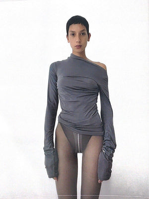 A woman standing wearing a coal-coloured draped top.