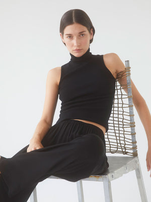 A model sitting on a chair wearing Paris Georgia's Black 04 Elemental Lounge Pants