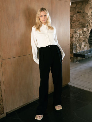 A woman wearing the Ivory Herb Shirt with black trousers with her hands in the pockets